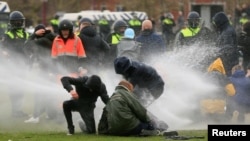 Vízágyúval oszlatja a rendőrség a járvány miatti lezárások ellen tüntető tömeget Amszterdamban, 2021. január 24-én. 