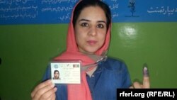 Женщина показывает свой документ и помеченный специальной краской палец после голосования на выборах президента Афганистана. Кабул, 14 июня 2014 года. 