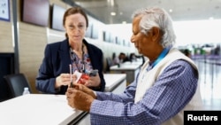 Muhammad Yunus își arată pașaportul și biletul de îmbarcare la aeroportul din Paris Charles de Gaulle miercuri, 7 august. Pleacă acasă, să devină premier. 