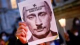 ITALY – A protester holds a picture of Russian President Vladimir Putin with a moustache and a symbol of swastika to resemble the Nazi dictator Adolf Hitler. Italy, February 25, 2022