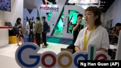 Visitors talk to staff members at a Google stand during the Global Mobile Internet Conference (GMIC) in Beijing, China, Friday, April 28, 2017.