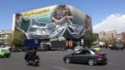 Commuters make their way past a billboard with a sentence saying "the Strait of Hormuz remains closed," on Tehran's Enqelab Square on April 5. 