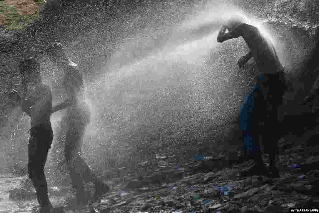 Karachi residents cool off as water sprays from a pipeline during a hot summer&#39;s day in a slum area of the Pakistani city on July 2. (AFP/Asif Hassan)