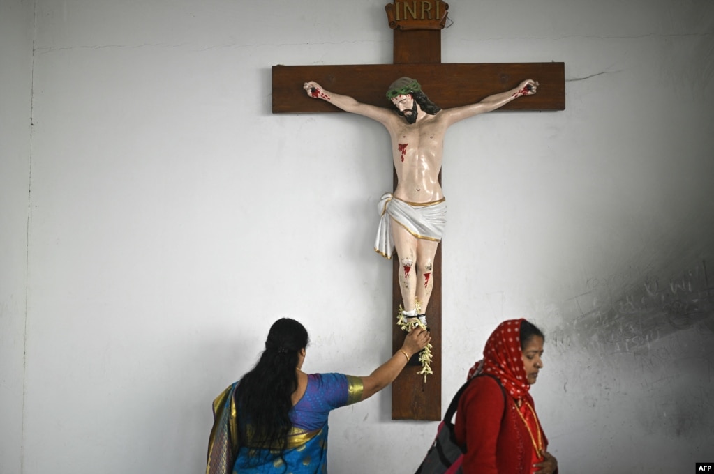 Dy besimtare duke u lutur para statujës së Krishtit në Bengaluru të Indisë.