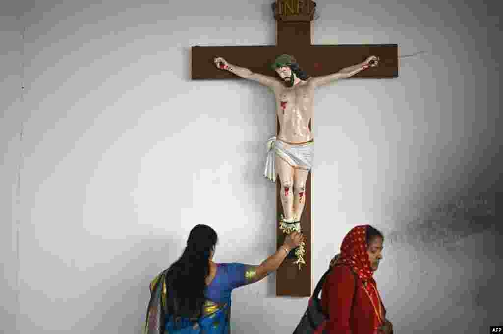 Dy besimtare duke u lutur para statujës së Krishtit në Bengaluru të Indisë.