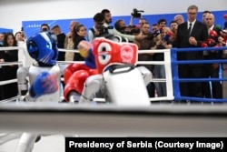 Serbian President Aleksandar Vucic (right) watches a robot boxing match at the Sabac factory.