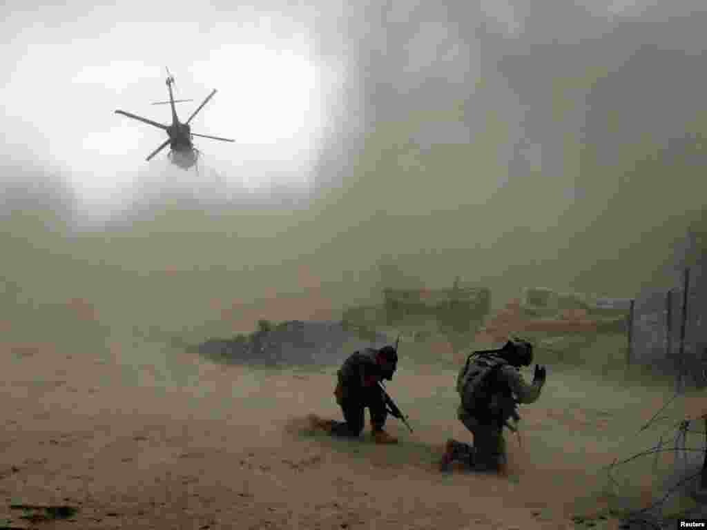 U.S. soldiers from the 101st Airborne Division shield themselves as a medivac helicopter takes off in the Arghandab Valley north of Kandahar on July 30. One soldier lost his leg and another was hit by shrapnel after an improvised explosive device (IED) blew up during a patrol near the base. Photo by Bob Strong for Reuters