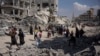 Palestinezët duke kaluar pranë ndërtesave të shkatërruara në Han Junis të Rripit të Gazës më 8 prill 2024. 