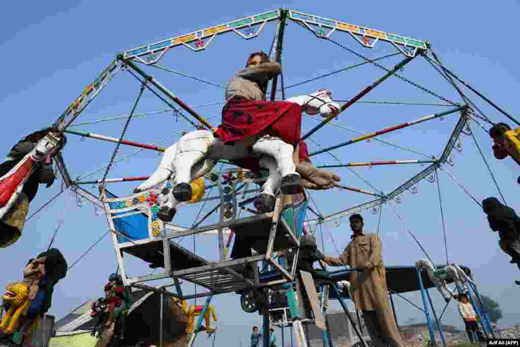 Children ride a merry-go-round in Lahore, Pakistan. (AFP/Arif Ali)