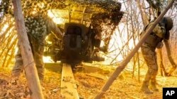 In this photo taken from a video released by the Russian Defense Ministry press service on December 11, Russian soldiers fire a D-20 howitzer toward Ukrainian positions in an undisclosed location.
