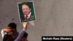 FILE: A supporter of the Pakistan Muslim League - Nawaz (PML-N) holds a portrait as he march towards the airport with others to welcome ousted Prime Minister Nawaz Sharif and his daughter Maryam, in Lahore on July 13.