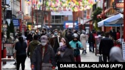 A koronavírus- járvány miatt arcmaszkot viselő gyalogosok London forgalmas utcáján sétálnak 2020. december 15-én 
