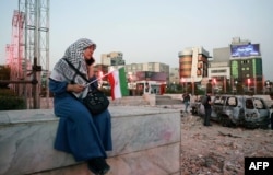 An Iranian woman sits close to a destroyed vehicle in Tehran on June 23.