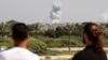 People in Lebanon's southern city of Tyre watch as smoke billows following Israeli strikes on September 23.