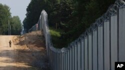 Poljski graničar patrolira uz metalni zod podignut između Poljske i Belorusije, 30. jun 2022.