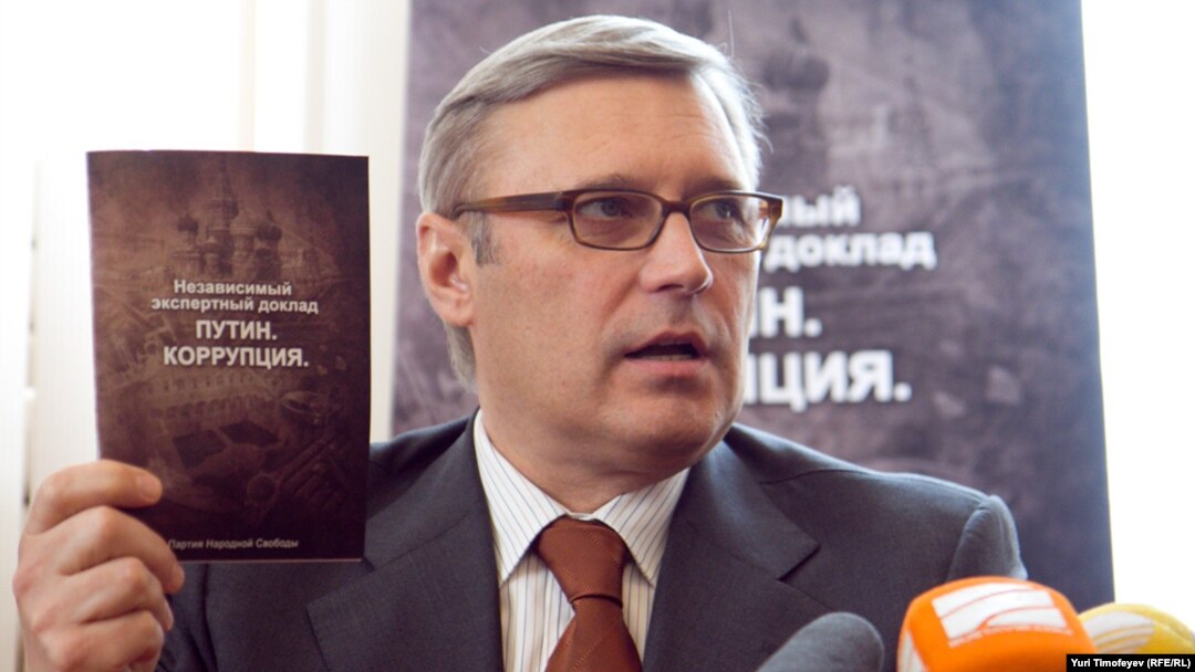 Former Prime Minister Mikhail Kasyanov holds up a copy of the report "Putin. Corruption," at its presentation on March 28.