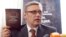 Former Prime Minister Mikhail Kasyanov holds up a copy of the report "Putin. Corruption," at its presentation on March 28.