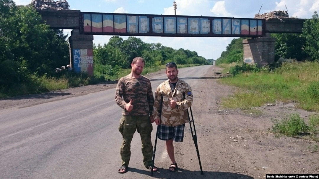 Denis Shchinkorenko (left) and Andrei Kamayev pose near a bridge painted with the word "Novorossia" in September 2015 in eastern Ukraine.