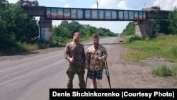 Denis Shchinkorenko (left) and Andrei Kamayev pose near a bridge painted with the word "Novorossia" in September 2015 in eastern Ukraine.