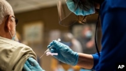 Një punonjëse shëndetësore vaksinon një pacient kundër COVID-19. SHBA, shkurt 2021. 