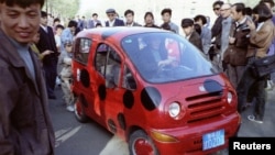 Muncitori din industria auto și elevi curioși admiră supermașina experimentală „Haișen” în provincia Jilin, din nord-estul Chinei.