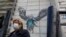 A woman walks in front of graffiti showing a doctor trying to help a patient with COVID-19, in the Moscow region.