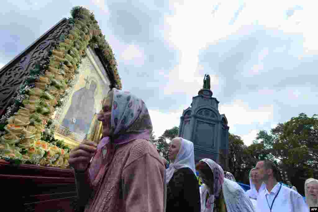 Orthodox believers wait in line to kiss an icon during the service and a ceremony in Kyiv.