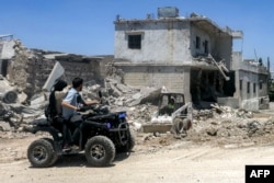 People ride an all-terrain vehicle past badly damaged buildings in in southern Lebanon following Israeli strikes on June 16.