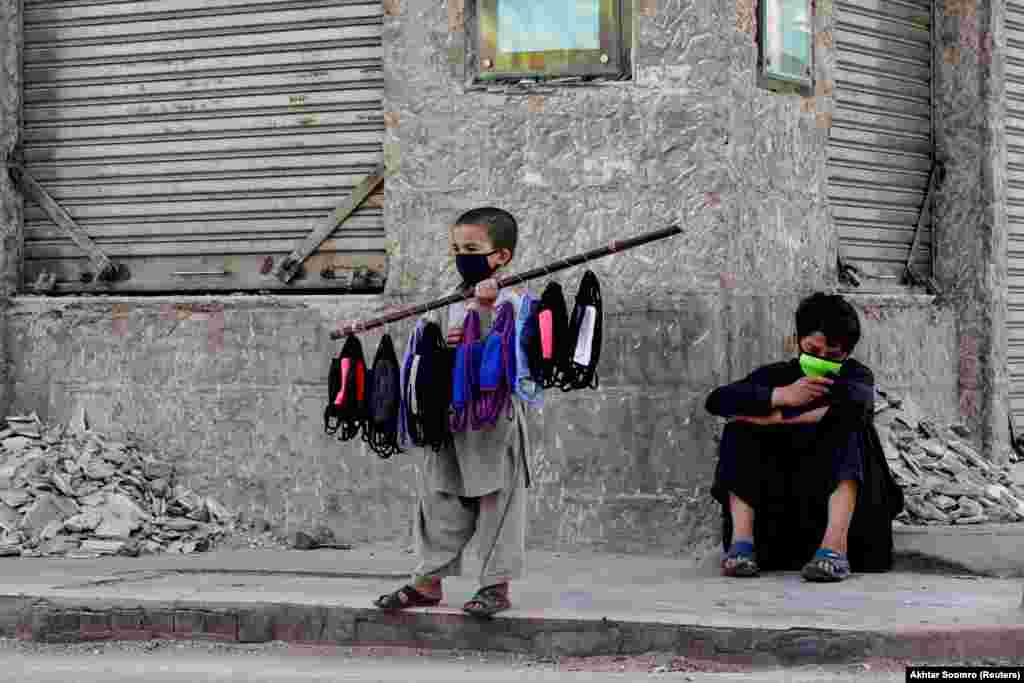 Seven-year-old Uzbillah stands with face masks on a stick selling them with his brother at the corner of a street during a lockdown in Karachi on March 31. (Reuters/Akhtar Soomro)