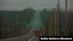 Автомобиль едет по дороге, покрытой сеткой для защиты от беспилотников, недалеко от города Славянск в Донецкой области, Украина, 27 октября 2025 года