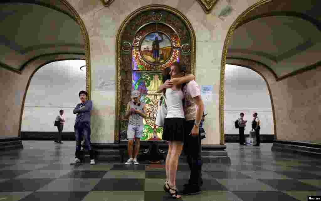 A couple in front of a stained glass panel at the Novoslobodskaya metro station