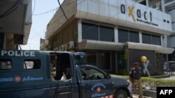 Pakistani policemen stand guard outside the offices of the Axact software firm in Karachi in May 2015.