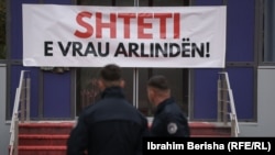 Pjesëtarë të Policisë së Kosovës duke shikuar hyrjen e ndërtesës së Qeverisë së Kosovës, në Prishtinë, më 26 tetor, pasi disa aktiviste vendosën një banderolë dhe hodhën ngjyrë të kuqe në shenjë proteste pas vrasjes së një gruaje në Pejë.