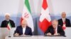 Swiss President Alain Berset (top right) and Iranian President Hassan Rohani (top left) look on as Johann Schneider-Ammann, head of the Federal Department of Economic Affairs, Education and Research (right) and Iran's Foreign Minister Mohammad Javad Zarif sign documents in Bern on July 3.