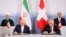 Swiss President Alain Berset (top right) and Iranian President Hassan Rohani (top left) look on as Johann Schneider-Ammann, head of the Federal Department of Economic Affairs, Education and Research (right) and Iran's Foreign Minister Mohammad Javad Zarif sign documents in Bern on July 3.