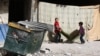 Children carry a chair in the street as people gather belongings in preparation for evacuation from eastern Ghouta.