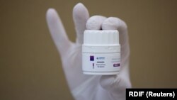 An employee demonstrates a container with new antiviral drug Avifavir, produced by manufacturer ChemRar and approved by the Russian authorities to treat patients suffering from COVID-19, at a storage in Moscow on June 10.
