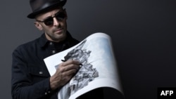 Артистът JR държи рисунка на проекта “Пещерата Пон ньоф”