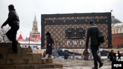 Прохожие рядом с инсталляцией Louis Vuitton на Красной площади в Москве. 28 ноября 2013 года.