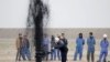 Iraq -- Iraqi workers stand near a pipeline as it ejects oil at Al Tuba oil field in Basra, February 19, 2015