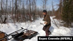 Житель эвенкийской деревни Чинонга грузит дрова, Россия, 2021 год