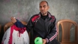 یک پدر فلسطینی و لباس دختر چهارساله‌اش مَسا که در دیرالبلح در نوار غزه کشته شد