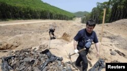 A researcher walks past remains and personal belongings of apparent victims of Stalin's purges.