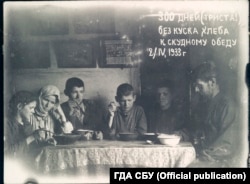 Mykola Bokan (la dreapta) și familia sa pozează mănâncând niște fierturi. Pe fotografie scrie „300 de zile” fără pâine. (Arhiva Serviciului de Securitate din Ucraina, fondul 6, cazul № 75489-fp, volumul 2)