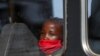 Djevojčica sa zaštitnom maskom gleda kroz prozor autobusa, Južna Afrika, 24. avgusta 2020. 