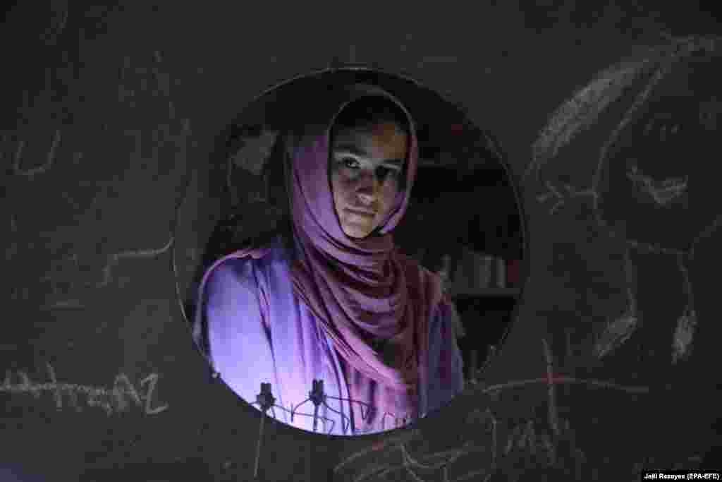 A young Afghan woman is reflected in a wall mirror while learning tailoring skills as part of a vocational training conducted by local women in Herat. (epa-EFE/Jalil Rezayee)