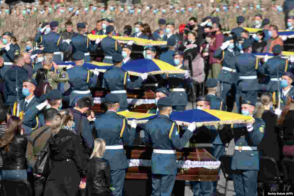 Ukrajinski vojnici stavljaju državne zastave preko kovčega kadeta vazduhoplovnih snaga tokom oproštajne ceremonije u Harkivu. Vojnici su poginuli u avionskoj nesreći u septembru (AFP/Sergey Borok)