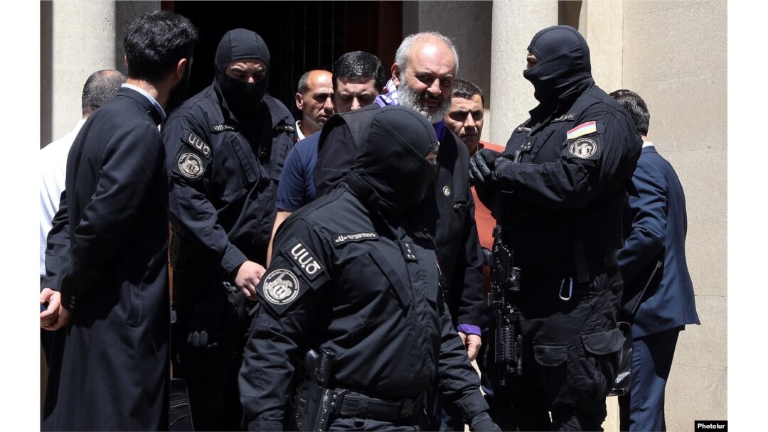 Ofițeri ai Serviciului Național de Securitate în timp ce îl arestează pe arhiepiscopul Bagrat Galstanian în capitala Armeniei, Erevan, pe 25 iunie 2025.