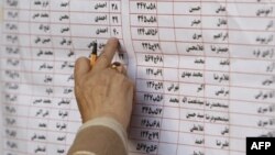 An Iranian voter chooses candidates from a list hanging on a bus designated as a polling station in Tehran during the March 2008 national elections.