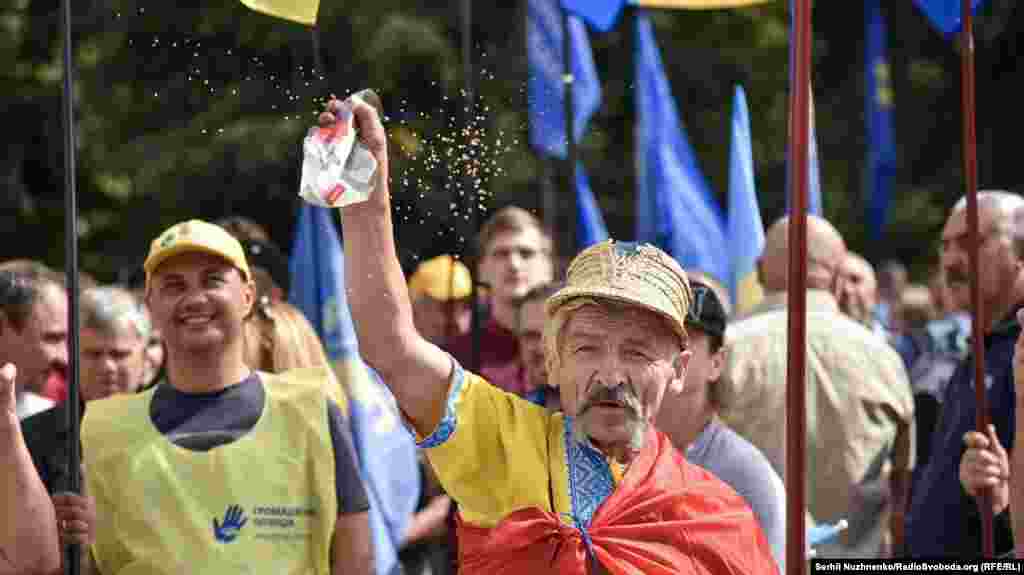 Чоловік сипле гречку в бік Верховної Ради під час мітингу з вимогою до депутатів зняти з себе недоторканність та змінити виборчу систему. Київ, 6 вересня 2018 року.&nbsp; БІЛЬШЕ ФОТОГРАФІЙ ПРО ЦЕ